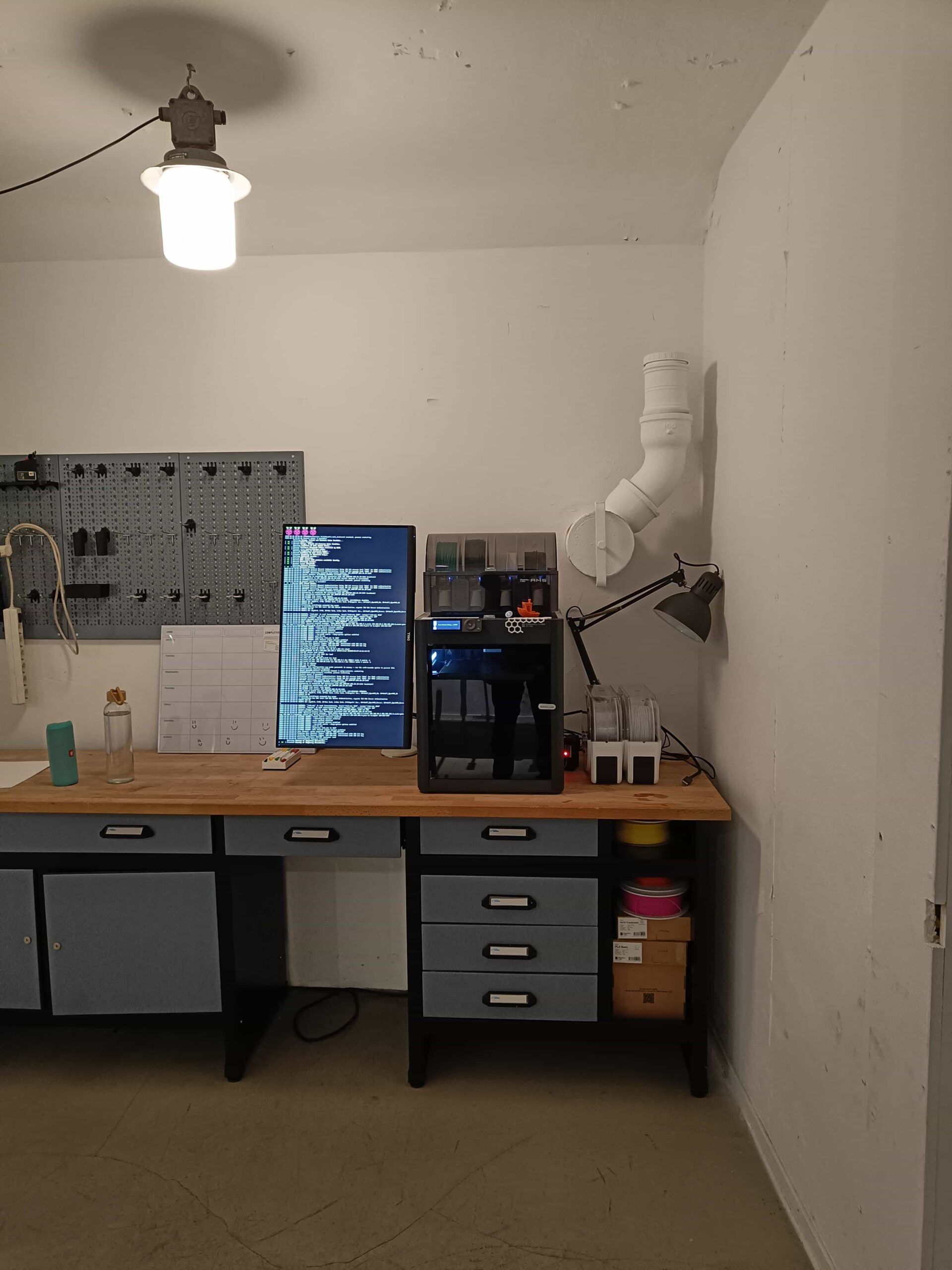 A Bambu Lab printer with spools of filament beside it on a wooden workbench
